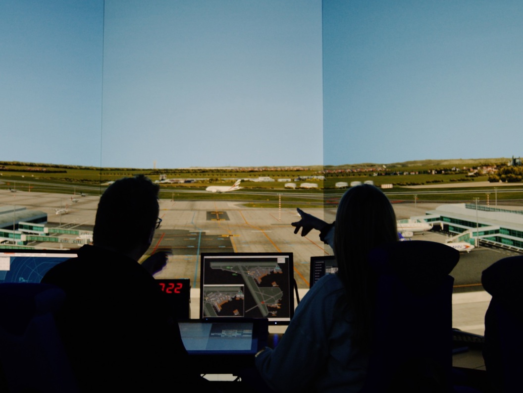 Lufttrafikkontrollører i et mørkt rom overvåker skjermer og administrerer operasjoner ved en simulering av en flyplasskontrolltårn