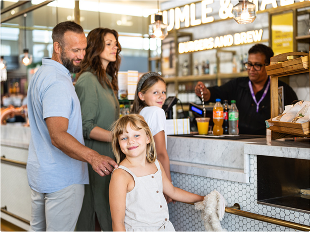 Family ordering food at a restaurant counter, with a server handing over drinks