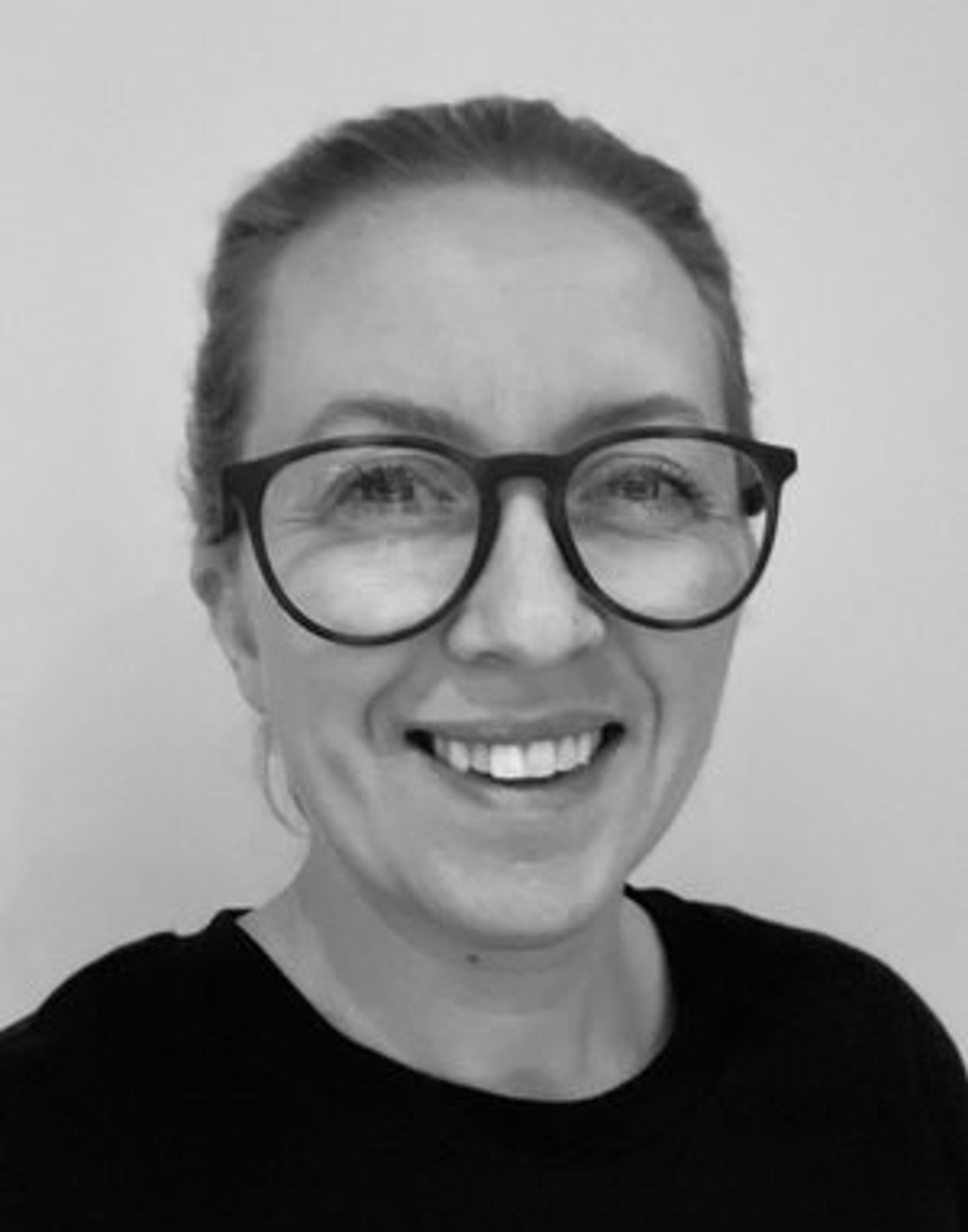 Smilende person med briller, svart-hvitt portrett