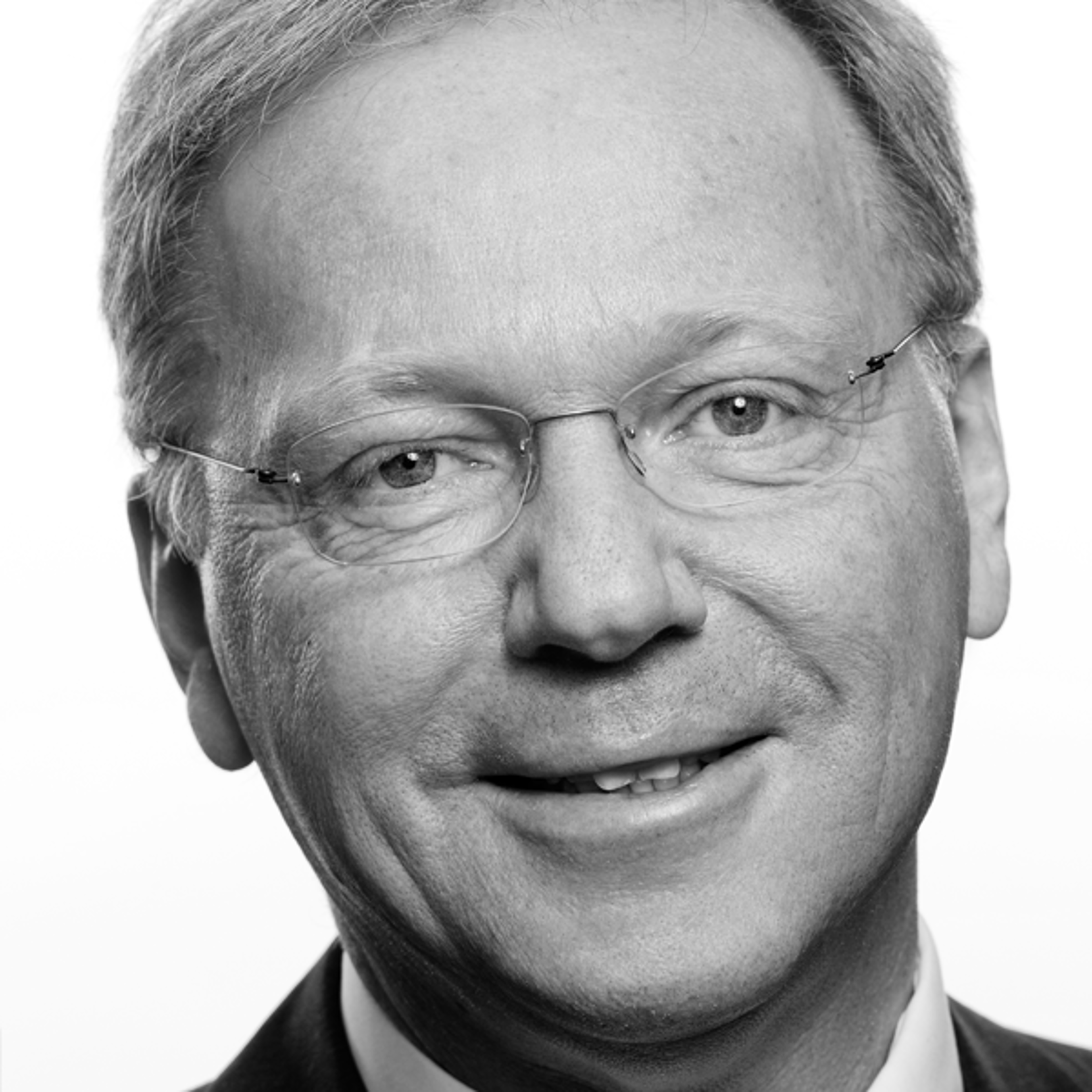 Smilende middelaldrende mann med briller i et svart-hvitt portrett