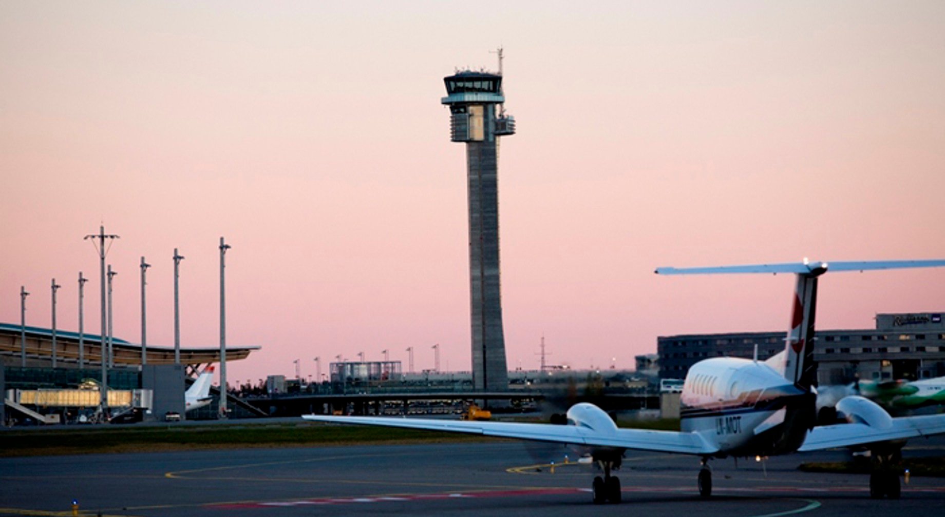 Airplane on the tarmac with airport control tower at sunset
