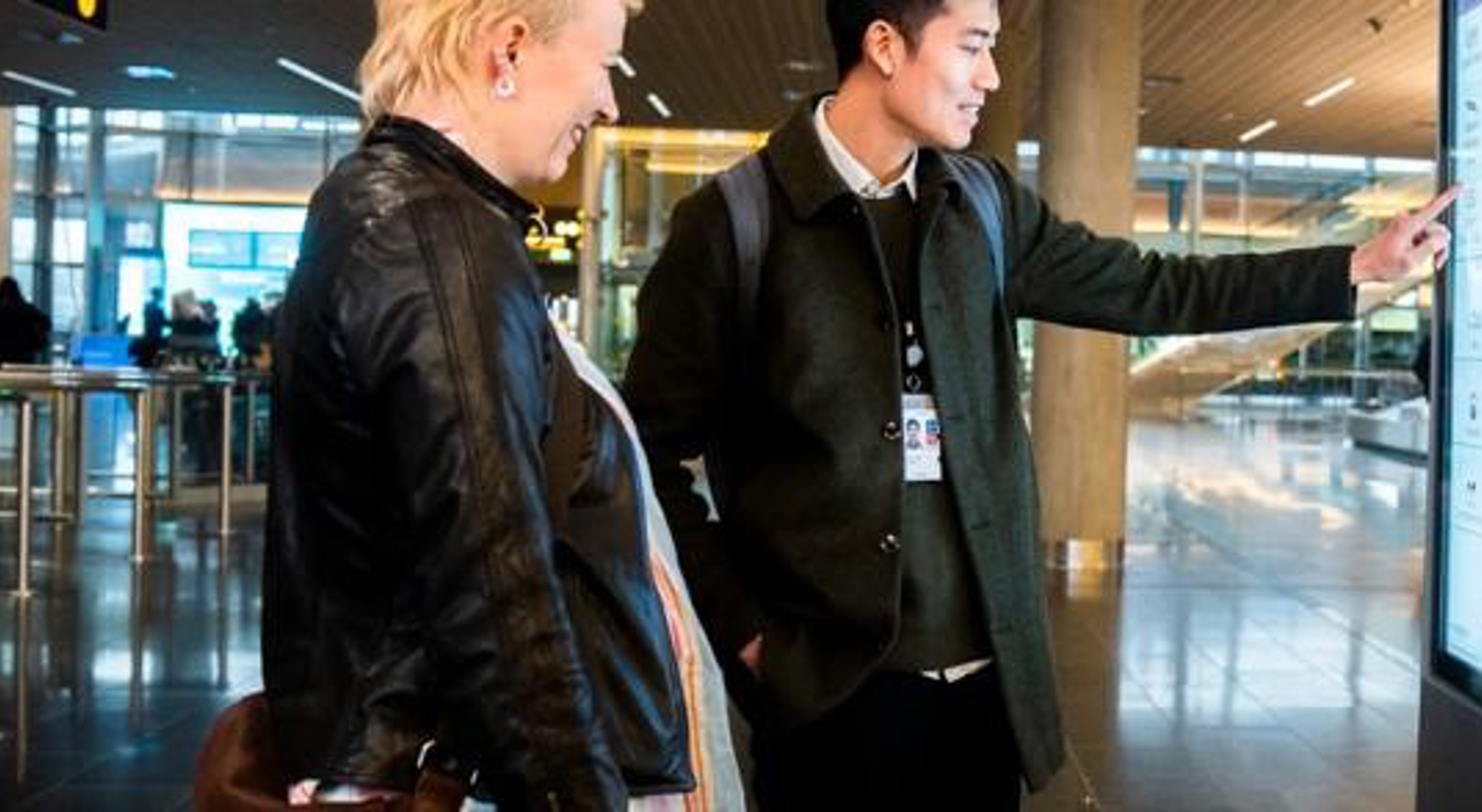 Kvinne peker mot skjerm i kontrollrom, smiler og ser fokusert ut. Skjermer med data i bakgrunnen.