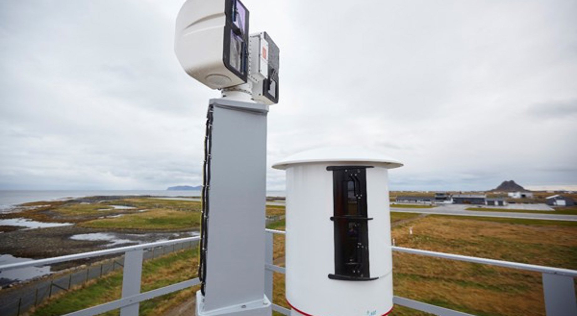 Værmåleutstyr på et kystobservasjonstårn med utsikt over havet og det gresskledde landskapet i overskyet vær