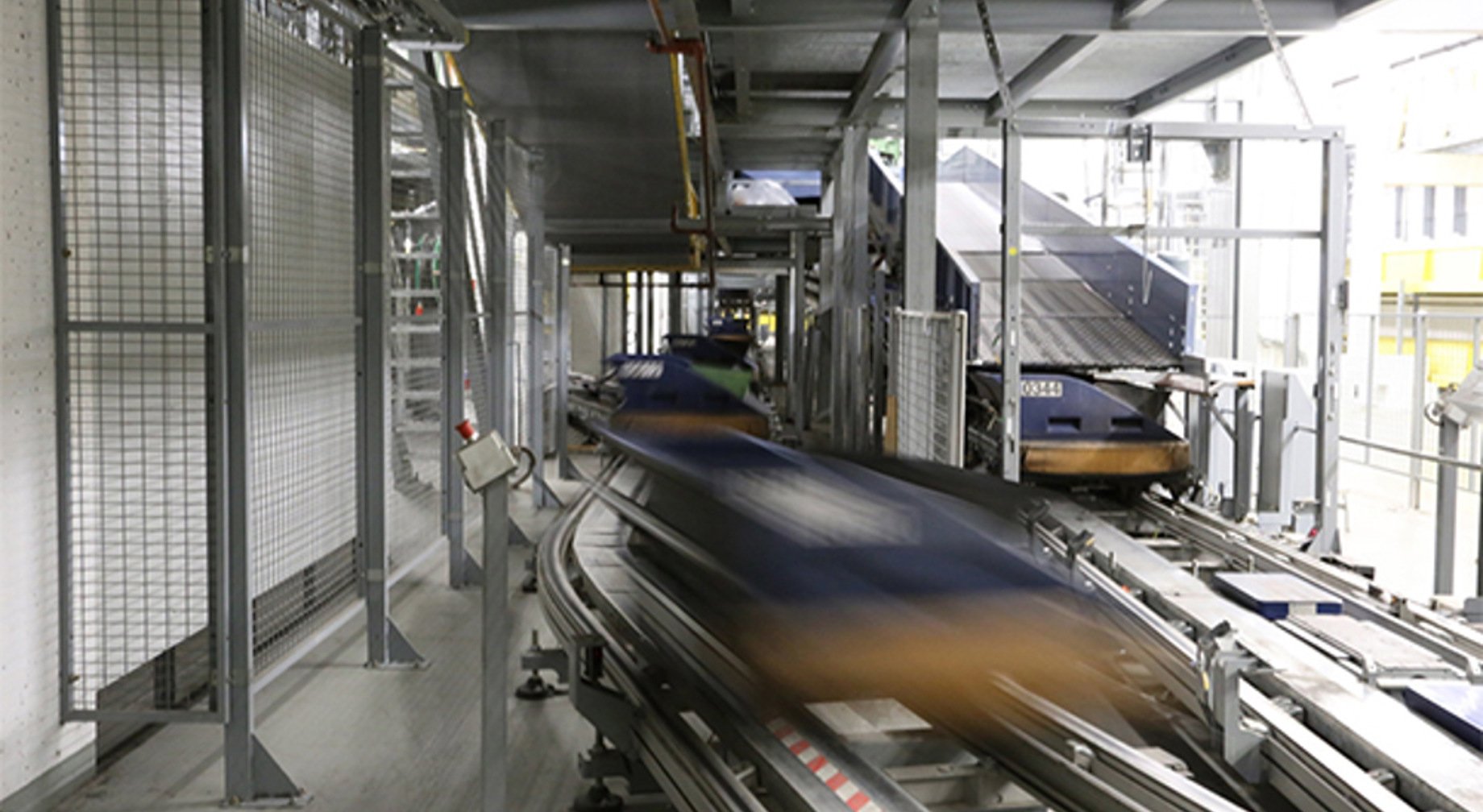 Automatisert pakke sorteringssystem i et industrielt anlegg, med hurtiggående transportbånd og avanserte maskiner for effektiv pakkebehandling